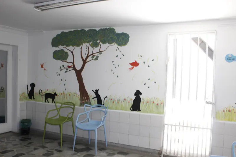 Mural de un árbol con perros y gatos en la sala de la clínica